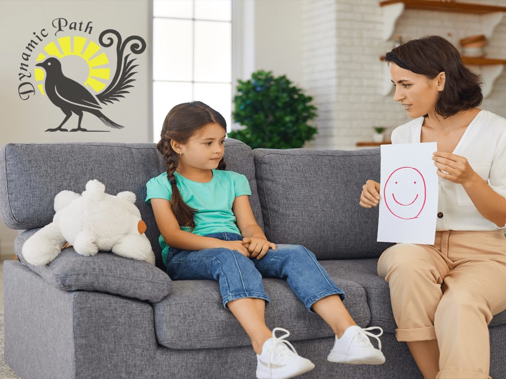 Child and adult on couch with red smiley face drawing and Dynamic Pathways logo featuring lyre bird and sunburst